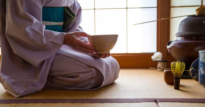 a woman holding a chawan preparing the Traditional Tea Ceremony in Japan