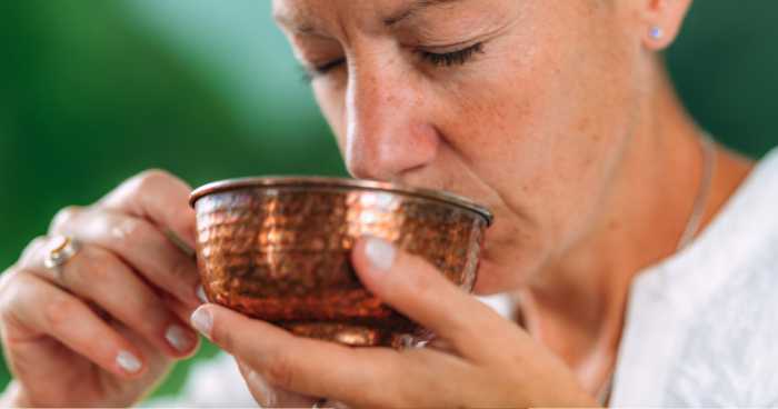 a woman drinking a bowl of matcha